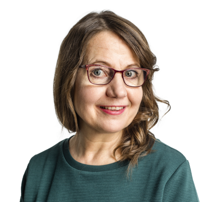 Kuvassa on Sirkku Ingervo, hartioista ylöspäin kuvattuna. Hän hymyilee ja hänellä on silmälasit, ruskeat kihartuvat hiukset ja vihreä paita.